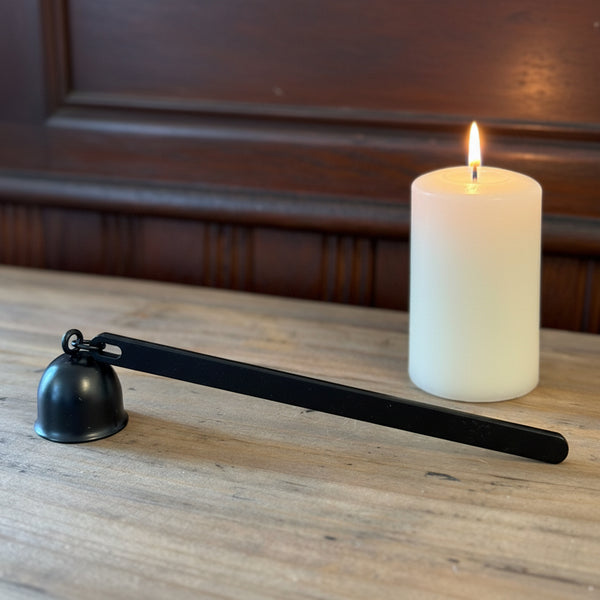 Flame On Main Candle Snuffer with a sleek black metal handle and bell-shaped cover resting on a wooden surface, perfect for safe candle extinguishing in home decor.