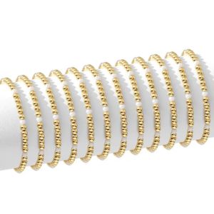 Multiple delicate gold beaded bracelets with small pearls displayed on a white stand, showcasing the Stretch Bead & Pearl Bracelet, 4mm, Gold, Priced individually, perfect for gifting and stylish jewelry decor.