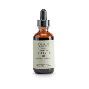 Bottle of Bourbon Barrel Foods Woodford Aged Aromatic Bitters, 2 oz, with dropper cap on a white background, styled for kitchen and entertaining gifts available at Knotty and Board.