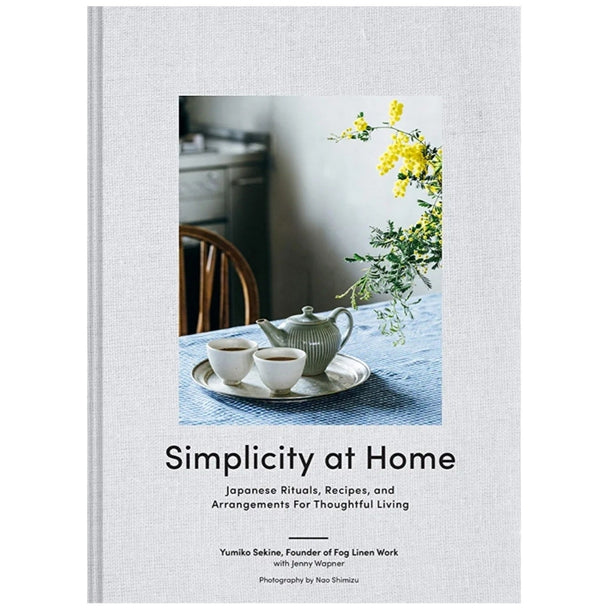 Cover of "Simplicity at Home - Yumiko Sekine" featuring a serene table setting with a teapot, two teacups, and yellow flowers in a vase, evoking calm and thoughtful living.