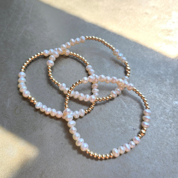 Three delicate Morgan & Me 3mm 14k Gold Filled Bracelets with Freshwater Pearls displayed on a smooth surface, highlighting elegant jewelry for stylish gifts or decor from Knotty and Board.