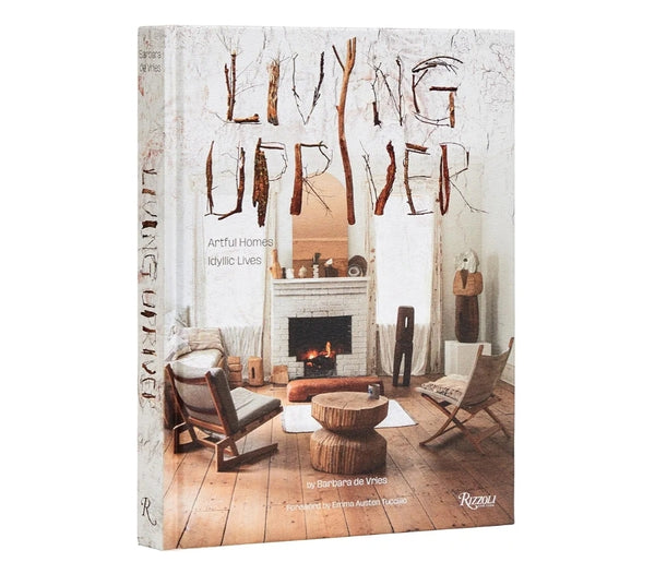 Book cover of Living Upriver featuring a cozy living room with wooden furniture and a burning fireplace, showcasing charming home decor and rustic style.